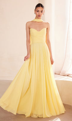 A woman in the Strapless Long Chiffon Prom Dress: Amoris T703 in light yellow, paired with a sheer scarf, stands indoors near a softly lit window.