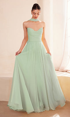 A woman stands indoors in the Strapless Long Chiffon Prom Dress: Amoris T703—a mint green, floor-length, strapless gown with a corset bodice and matching scarf—elegantly holding the skirt of her formal evening dress.