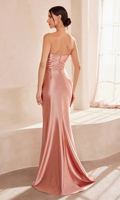 A woman stands with her back to the camera in a softly lit room, wearing the Classic Strapless Long Prom Dress: Amoris T704—an elegant, floor-length rose gold satin gown from Cinderella Divine's collection.