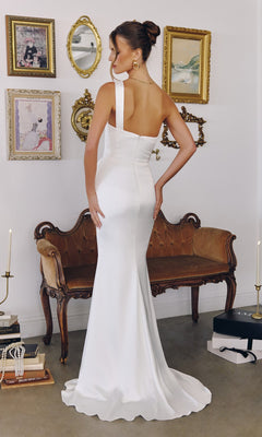 A woman in the Long Off-White Prom Dress: Amoris T727W stands before a vintage sofa, framed art, and candle holders in an elegant room.