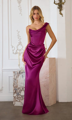 A woman stands indoors next to a marble pedestal and ornate white wall, wearing the Amoris T727 long prom dress in berry satin with a one-shoulder asymmetric neckline.