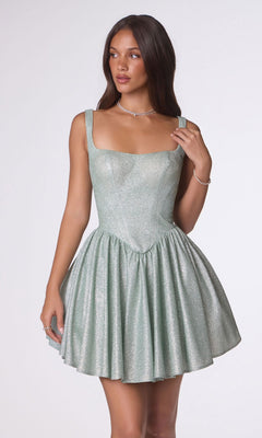 A woman wears the Amoris T738 short homecoming dress in sage, featuring a sleeveless fitted bodice and flared skirt crafted from shimmering stretch fabric, standing against a plain light background.
