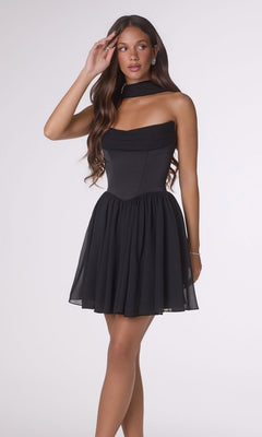 A woman stands against a plain light background wearing the Amoris T740 Short Homecoming Dress in black, featuring a satin bodice, flared chiffon skirt, and a matching choker.