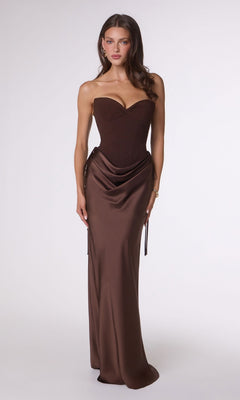 Woman stands facing forward, wearing the Amoris T747 long prom dress in Espresso—a strapless satin gown with a fitted bodice and draped skirt—against a plain light background.