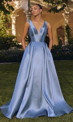 Outdoors, a woman wears the Amoris T814—a floor-length smoky blue mikado prom dress featuring an a-line silhouette, sleeveless design, deep V-neckline, and convenient pockets.