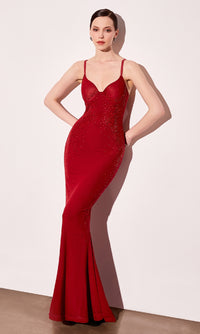 Woman modeling a long fitted red evening gown standing in front of a white wall.