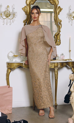 A woman in the Amoris T906 mocha long prom dress, featuring a one-shoulder design and chiffon cape overlay, stands before an ornate gold mirror and table adorned with decorative accents and shopping bags.