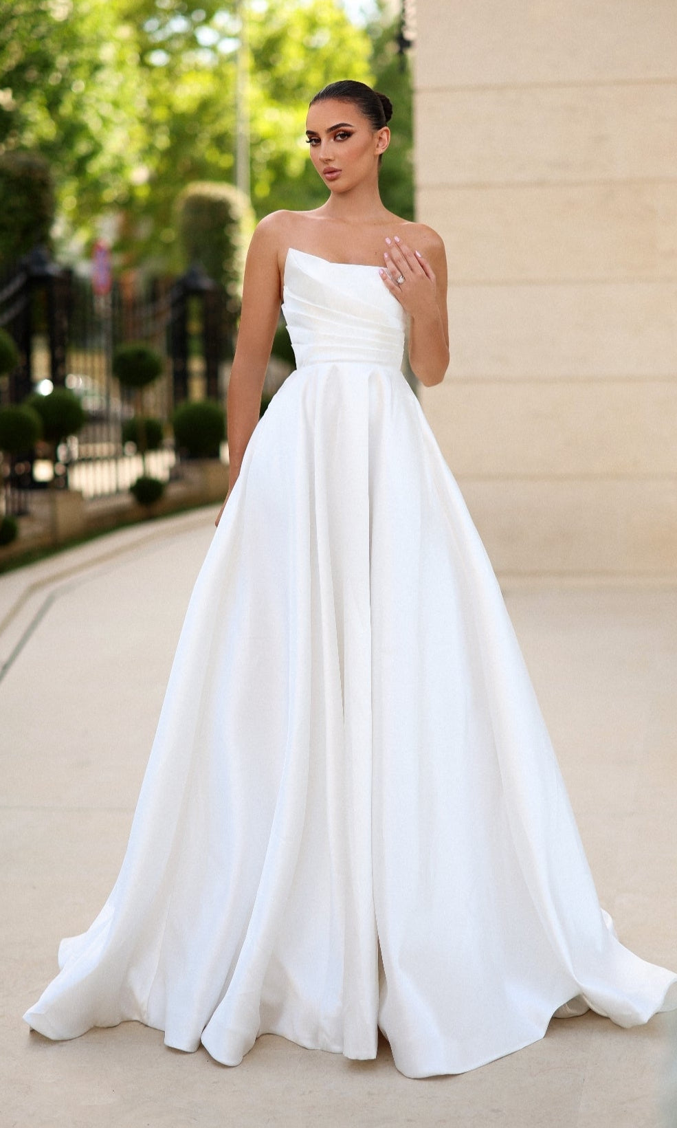 Woman standing outdoors in the Tina Holly TE302—a strapless, full-length white prom dress featuring a fitted bodice and flowing skirt.