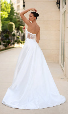 A woman poses outdoors with her back to the camera, wearing the Strapless Long White Prom Dress: Tina Holly TE302, featuring a structured bodice and flowing skirt.