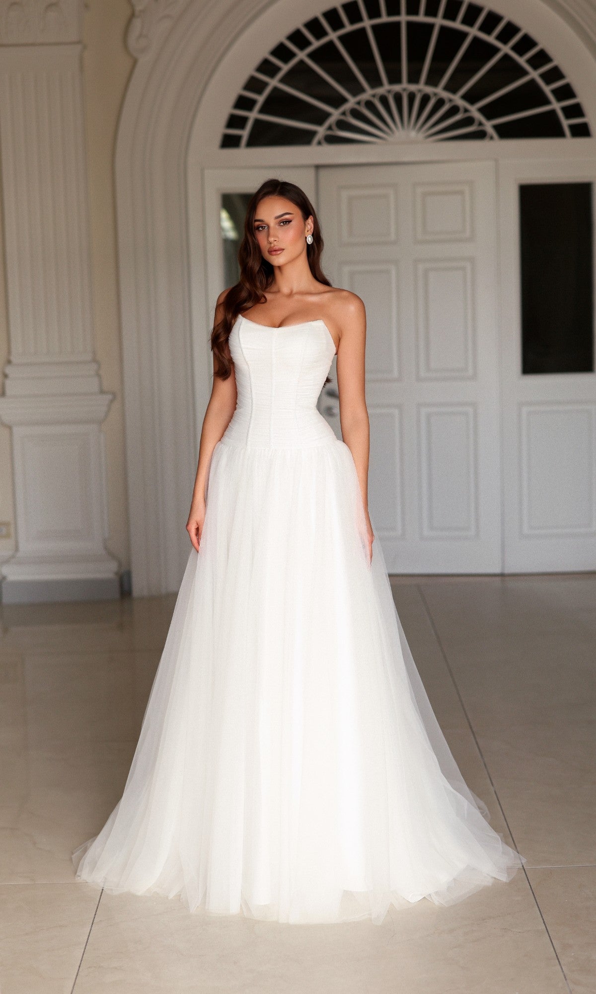 Tina Holly TE710 floor-length white wedding dress with a strapless corset bodice and a full tulle skirt.