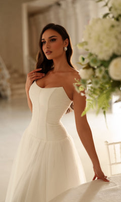 Tina Holly TE710 wedding dress featuring a strapless, floor-length white gown with a corset-style bodice and a full tulle skirt.
