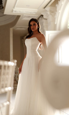 Woman wearing a Tina Holly TE710 long wedding dress featuring a strapless corset bodice and a full tulle skirt.