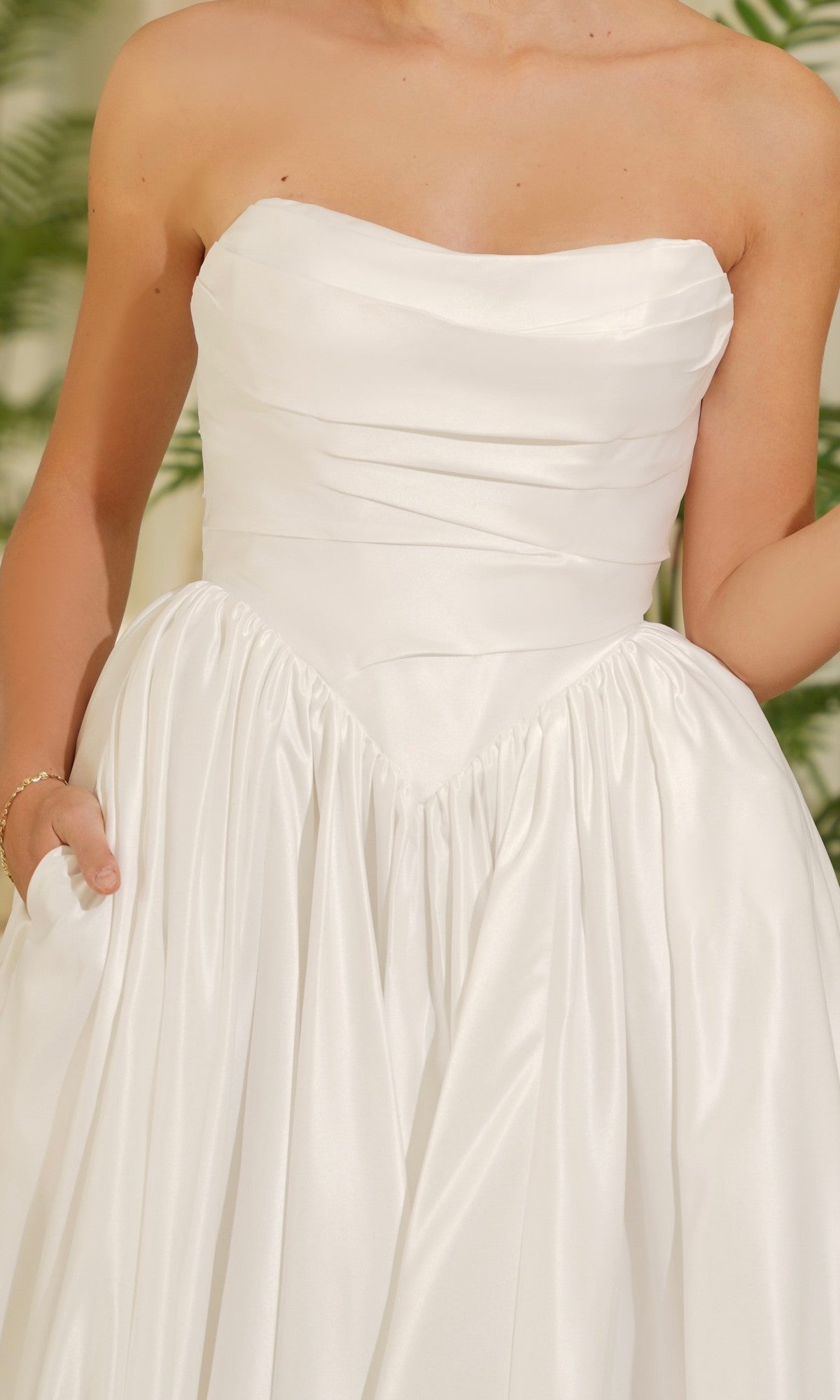 A person wearing the Long Off-White Satin Dress: Tina Holly TE810, which features a strapless design, fitted bodice, basque waistline, and a gathered full skirt.