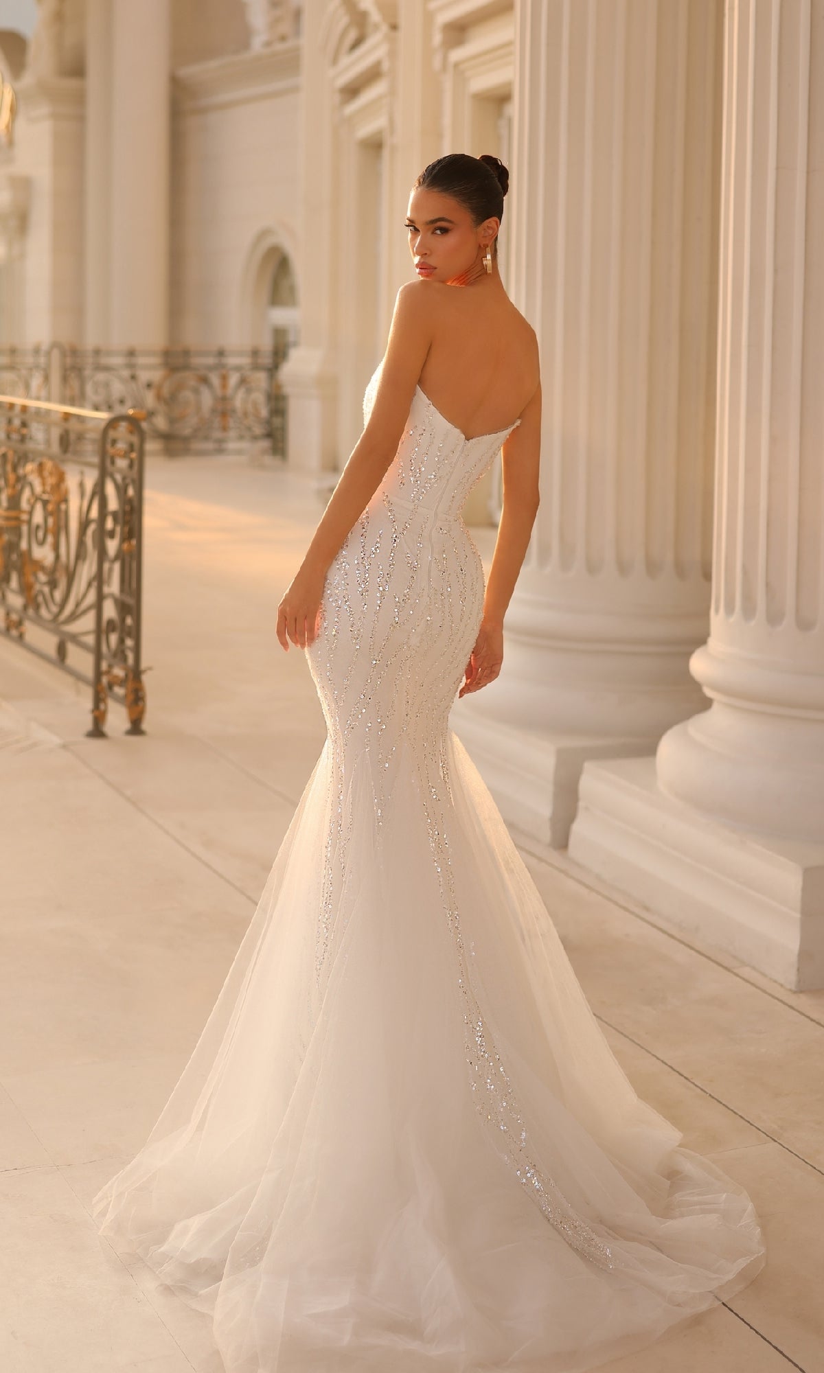 Wearing the Strapless Long Glitter Prom Gown Tina Holly TK807, a woman stands near ornate railings and white columns, looking over her shoulder.