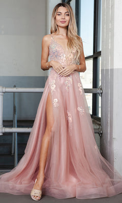A woman stands indoors in the Floral-Embellished Pastel Prom Ball Gown TM1003, showcasing blush pink tulle, floral details, a high slit, and open-toe heels.