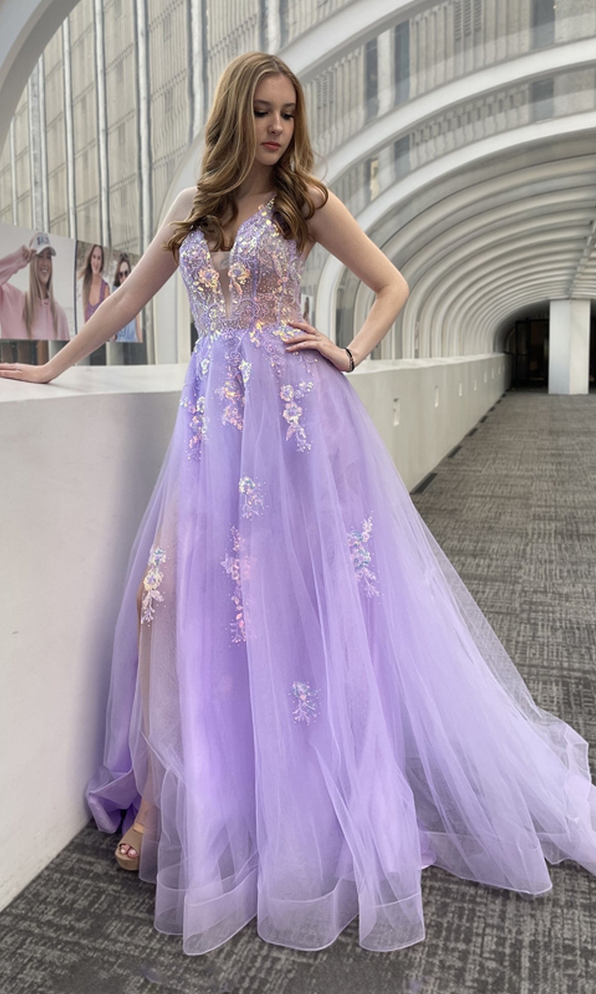 A woman stands in a modern, white arched hallway wearing the Floral-Embellished Pastel Prom Ball Gown TM1003.
