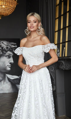 A woman in the Long White Lace Formal Dress: Tina Holly TK023W stands indoors near a large classical statue and ornate decor.