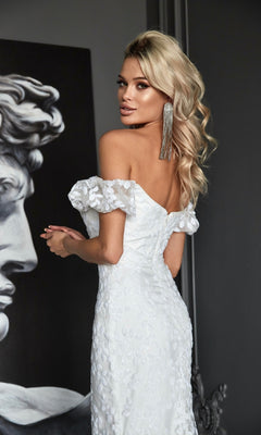 A woman wearing the Off-Shoulder White Formal Dress: Tina Holly Tk024W poses indoors beside a grayscale classical sculpture.