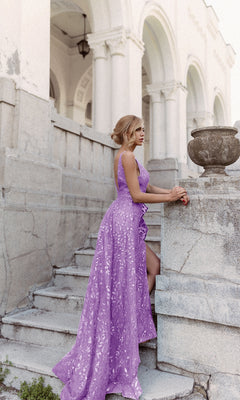 Wearing the Ruffle Overskirt Long Prom Gown: Tina Holly TW025, a woman stands on stone steps beside a large planter in front of a white classical-style building.
