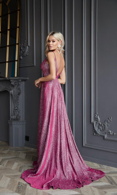 A woman wears the Long Glitter A-Line Prom Dress, Tina Holly TW079—a sparkly pink, floor-length gown with a deep v-neck and open back—while standing in an elegant room with gray paneled walls and ornate moldings.