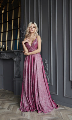 A woman stands indoors in front of a gray ornate wall and mirror, wearing the Long Glitter A-Line Prom Dress by Tina Holly TW079 with a deep neckline.