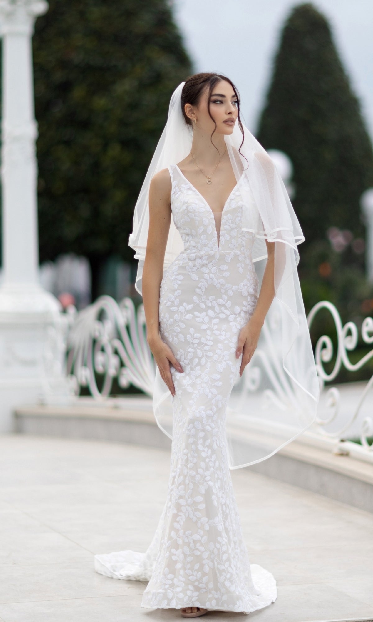 A woman wearing the Long White Sequin Formal Dress: Tina Holly TW108 stands outdoors near a white railing and greenery.