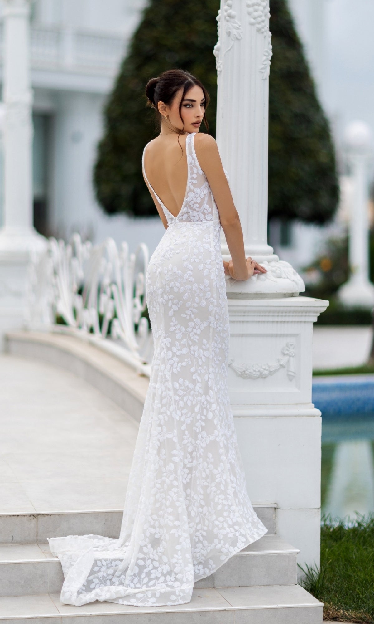A woman wearing the Long White Sequin Formal Dress: Tina Holly TW108 stands on outdoor steps by a white column, looking over her shoulder.