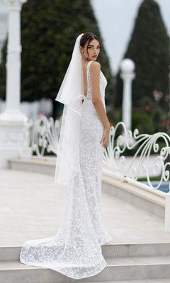 A woman in the Long White Sequin Formal Dress: Tina Holly TW108 stands outdoors on stone steps, looking over her shoulder.
