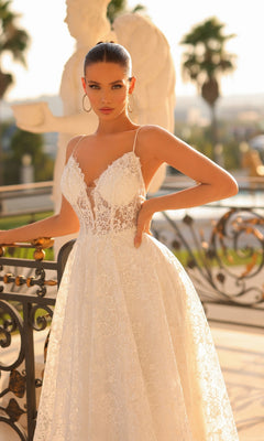 A woman poses outdoors by a decorative railing in the Traditional Lace Bridal Gown: Tina Holly TW133, with statues and palm trees visible in the background.