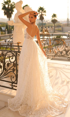 A woman in the Traditional Lace Bridal Gown: Tina Holly TW133 stands on an ornate balcony, gazing over her shoulder with one hand on her head.