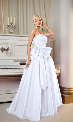 A woman wearing the Long Formal Dress: Tina Holly TW603, a strapless taffeta evening gown with detachable bow and A-line skirt, stands before a white piano and candelabra in an elegant room.