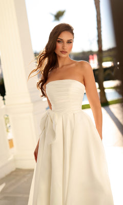Tina Holly TW621 long wedding dress, a strapless white gown featuring a fitted bodice, pleated skirt, and a bow tie at the waist.