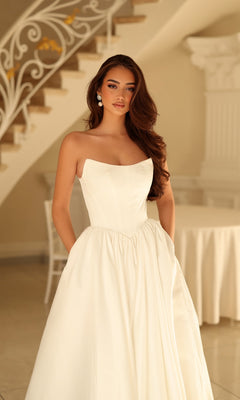 The Tina Holly TW622 is a strapless white wedding dress with a fitted bodice and a full, A-line skirt with pockets.
