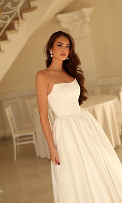 A woman wearing a Long Wedding Dress: Tina Holly TW622, a strapless, floor-length white satin bridal gown with a fitted bodice and a full, A-line skirt.