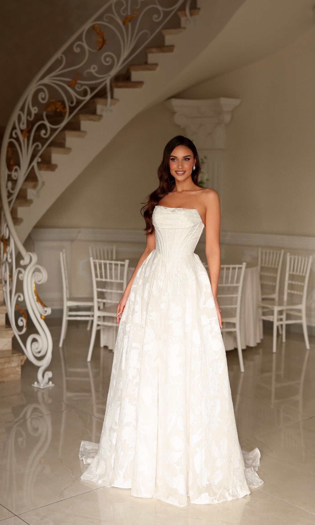 A woman wearing the Long Wedding Dress: Tina Holly TW623, a strapless, floor-length A-line bridal gown with a textured floral pattern.