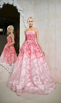 A woman in the Tina Holly TW624 long formal dress stands beside an ornate mirror in a light-colored room, her pink strapless A-line gown shimmering with the elegance of floral-patterned organza jacquard.