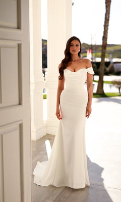 Woman wearing a white, off-the-shoulder, floor-length fit-and-flare Long Wedding Dress: Tina Holly TW628 with a sweetheart neckline and ruched bodice.