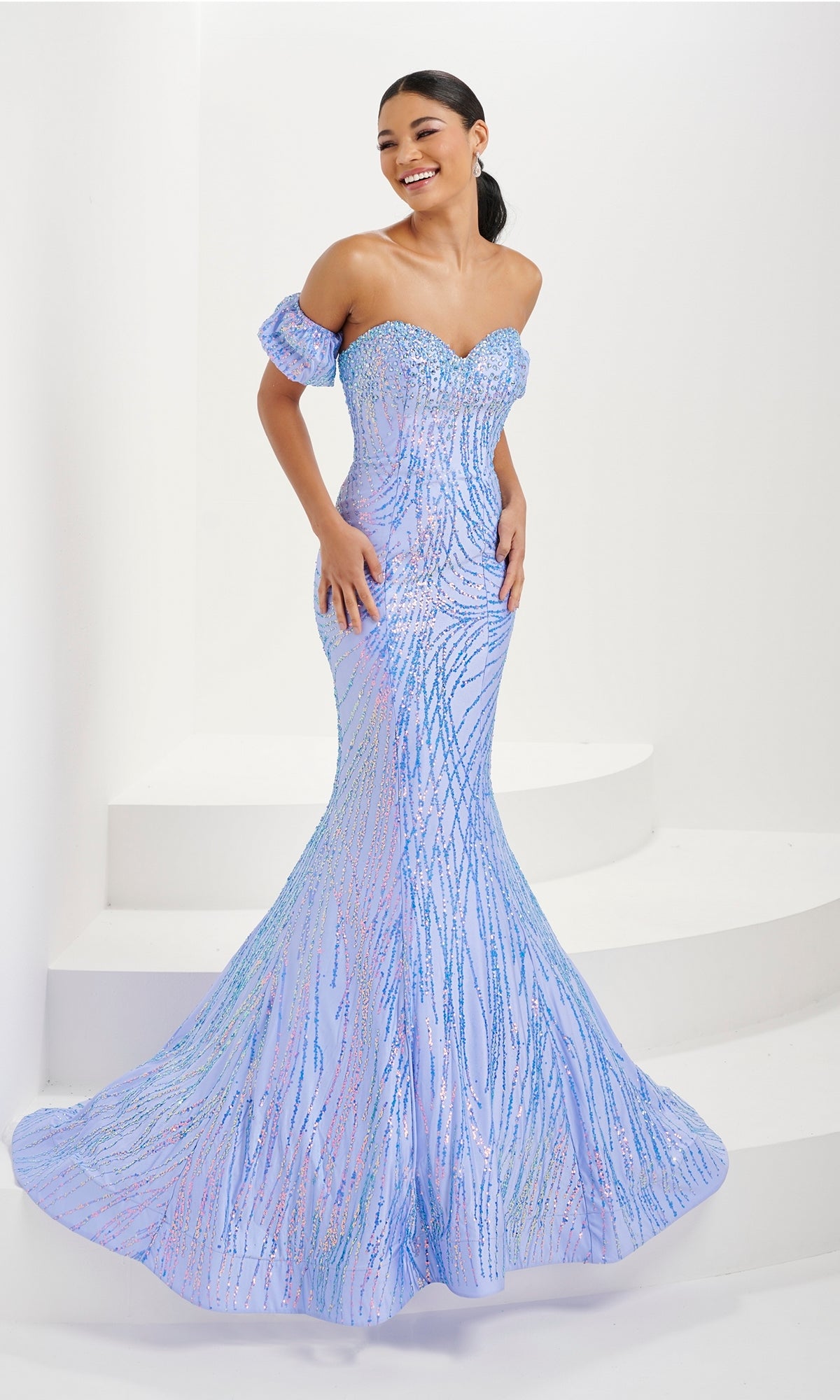 Woman wearing the Tiffany Glitter-Print Black Mermaid Prom Dress 16071, a fitted strapless mermaid gown with sparkling details, standing on white steps against a plain background.