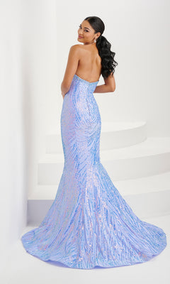 Woman in the Tiffany Glitter-Print Black Mermaid Prom Dress 16071 stands on a white curved staircase, looking over her shoulder. The strapless fitted gown features glitter details and a dramatic flared train.