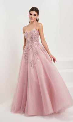A woman wearing the Tiffany Backless Tulle Ball Gown Prom Dress 16072 in light pink, featuring floral embroidery and thin straps, poses against a plain white background.