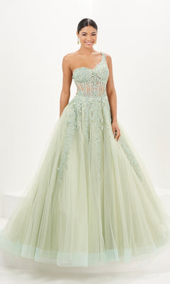 A woman wearing the Tiffany One-Shoulder Sheer Corset Prom Dress 16096, an a-line light green gown with floral appliques and a tulle skirt, stands smiling against a white background.