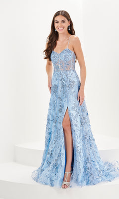 A woman wears the Tiffany A-Line Glitter Tulle Prom Dress 16097 in light blue, featuring sequined glitter print, floor-length design, a thigh-high slit, and thin straps, standing against a white background.