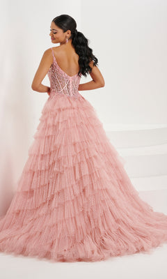 A woman poses with her back to the camera in the Tiffany Ruffled Glitter Tulle Prom Ball Gown 16099, showcasing its sparkling tulle skirt and fitted, beaded corset bodice against a plain white background.