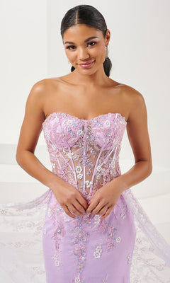 Woman wearing the Tiffany Strapless Sheer Corset Prom Dress 16107 in lilac, featuring floral sequin embroidery and sheer details, standing against a light background.