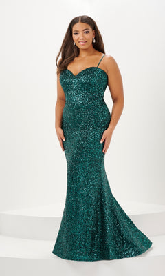 A woman stands on a white platform against a plain background, wearing the Tiffany Plus-Size Designer Sequin Prom Dress 16121—a fitted, floor-length dark green gown with thin straps.