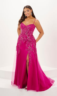 A woman models the Tiffany Long Plus-Size Floral Tulle Prom Dress 16127, a bright pink, floor-length A-line gown with thin straps, floral embellishments, and a front slit, standing against a plain white background.