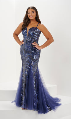 A woman wears the Tiffany Plus-Size Sequin Mermaid Prom Dress 16132, featuring a floor-length navy design with sequins, thin straps, a plunging v-neckline, and a tulle mermaid skirt.