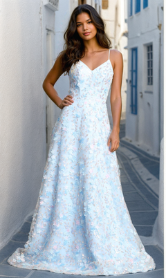 A woman stands in a narrow alley wearing the Long Light Blue Floral Prom Dress: Chicas CHF3092, featuring delicate 3-D flowers and thin shoulder straps.