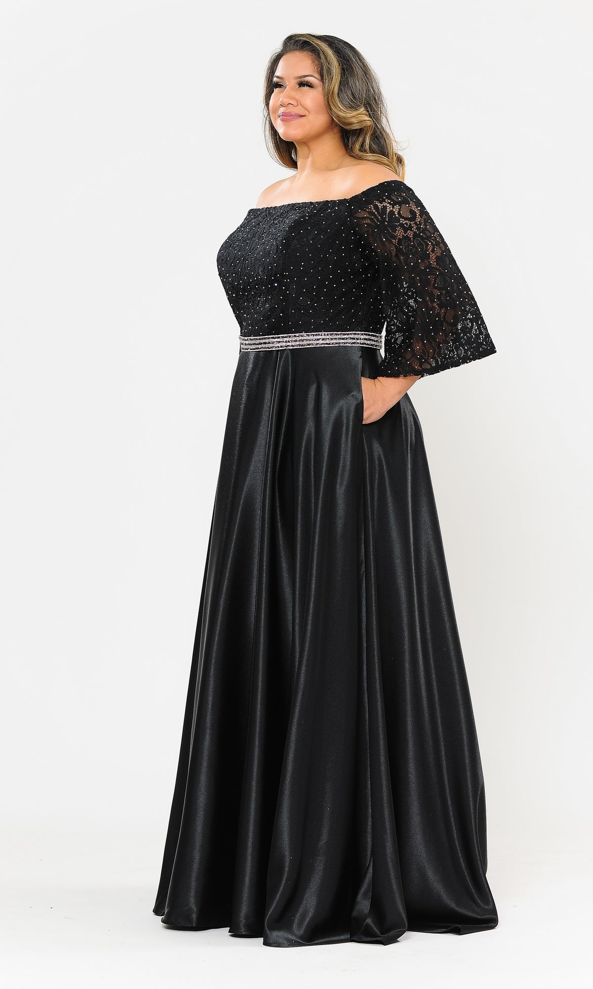 A woman poses against a plain white background wearing the Bell-Sleeve Plus-Size Long Prom Dress W1008, a floor-length black gown featuring lace sleeves, a beaded bodice, and a jeweled waistband.