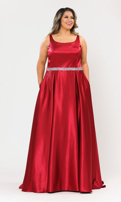 A woman models the Sleeveless Plus-Size Long Belted Prom Dress W1010 in red, featuring a floor-length design and silver beaded waistband, standing against a plain white background.